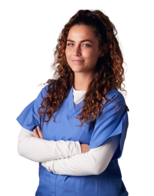 young woman with long curly brown hair wearing blue scrubs with a long sleeved white shirt underneath while she crosses her arms