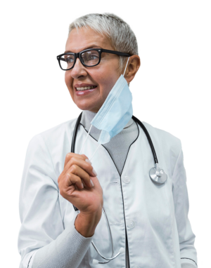 Woman with short white hair and black rimmed glasses removing a face mask with her right hand wearing a white nurse's coat and has a stethoscope hanging around her neck